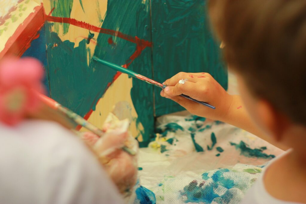 person holding paint brush painting on white and blue floral textile